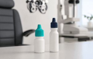 Two prescription eye drop bottles on an exam room table, illustrating medication questions before and after cataract surgery at Wellish Abrams Vision Institute.