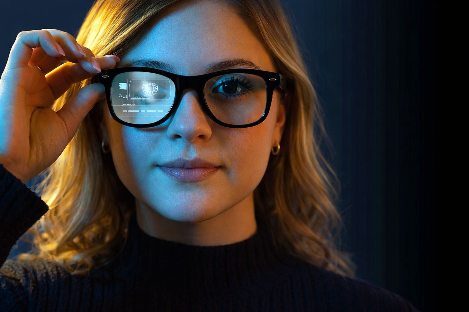 A woman with black-rimmed glasses adjusts her glasses while looking at the camera, illuminated by blue lighting.
