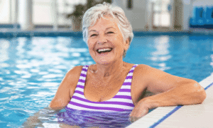 Active senior woman taking a break from water aerobics in a pool, illustrating lifestyle goals related to cataract lens options at Wellish Abrams Vision Institute