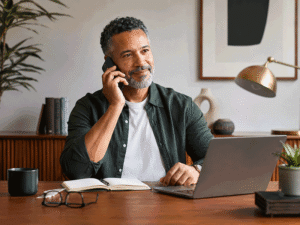 55-year-old man speaking with his eye doctor by phone in a warm home office, illustrating support for glaucoma eye drops at Wellish Abrams Vision Institute.
